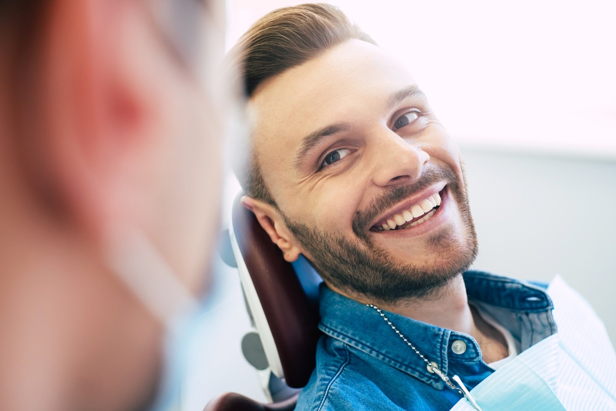 A man sitting in the dentist chair smiling.