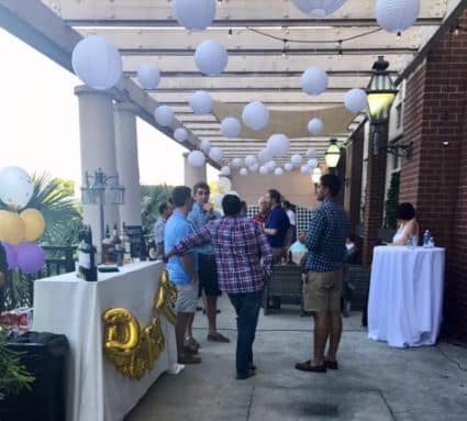 A group of people standing around tables with drinks.