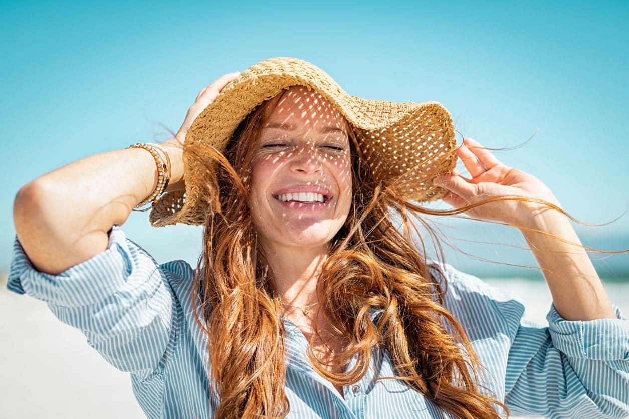 A woman with long hair and a hat on.