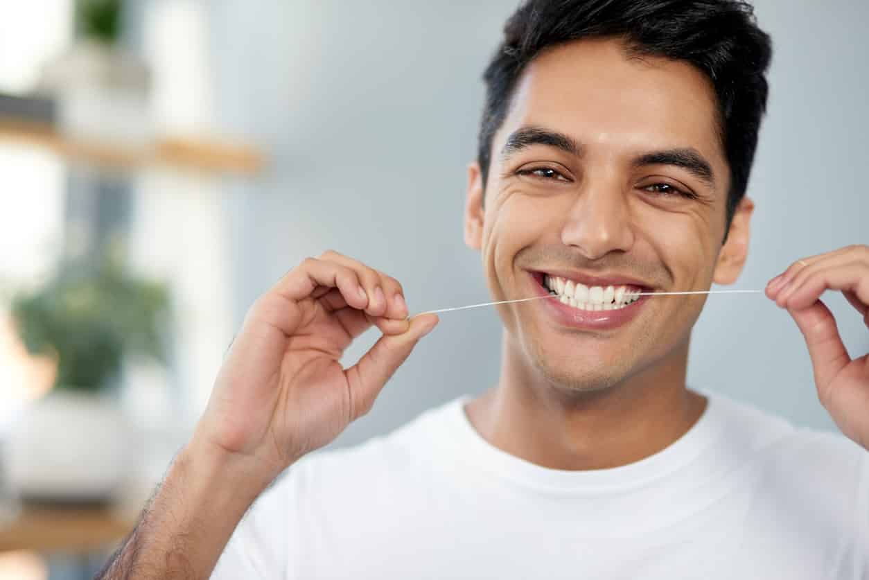 A man is holding a tooth brush in his mouth.