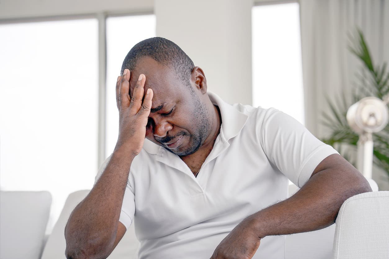 A man sitting on the couch holding his head